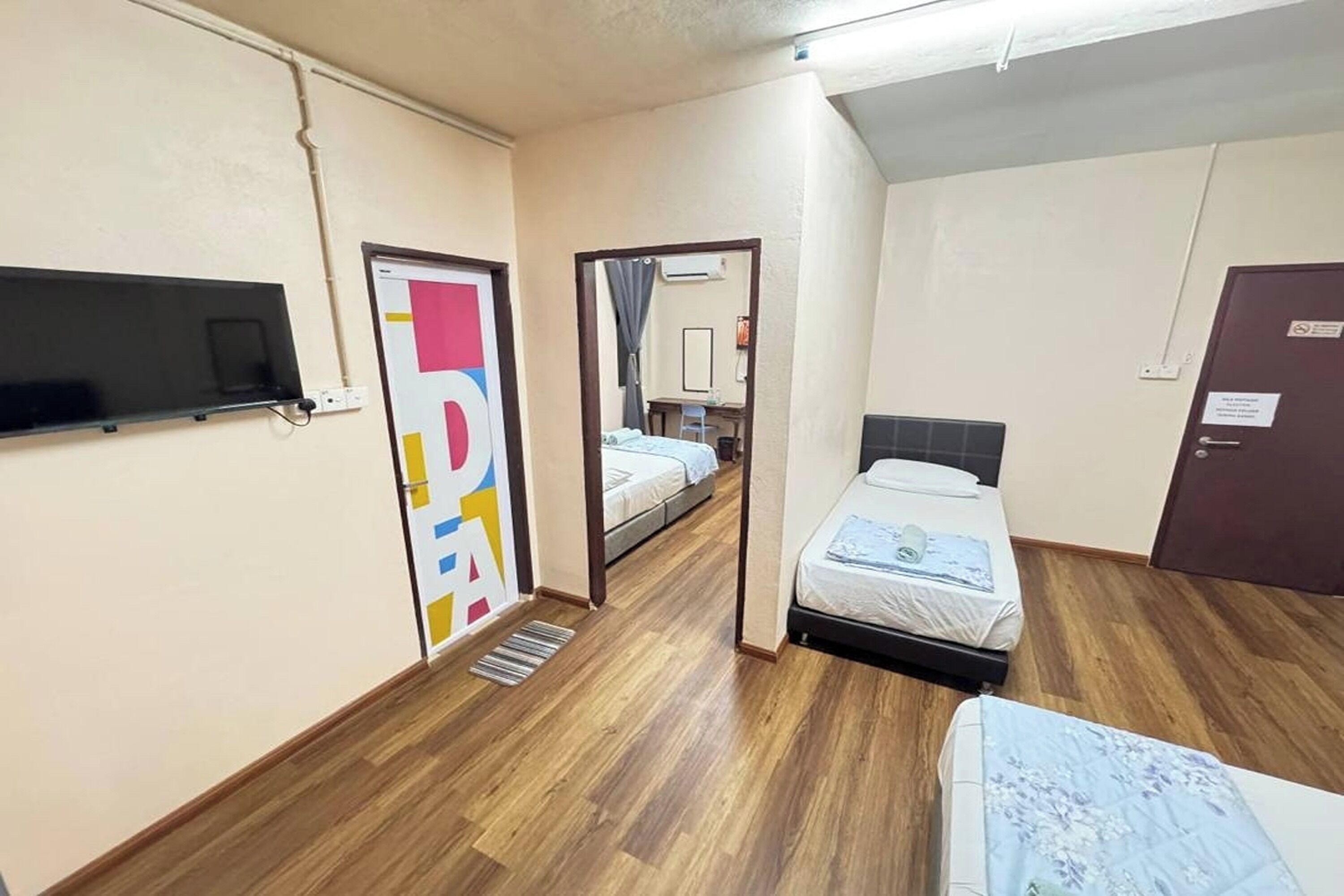 Hotelkamer met een bed, een televisie, een spiegel en een deur met een bordje.