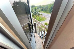 Un balcón con vista a una carretera y palmeras.