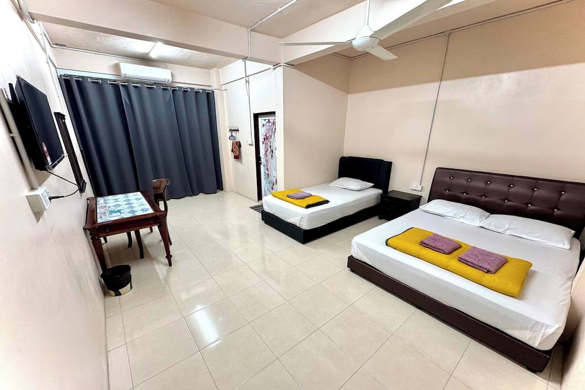 Una habitación de hotel con dos camas, un escritorio, una silla y un ventilador de techo.