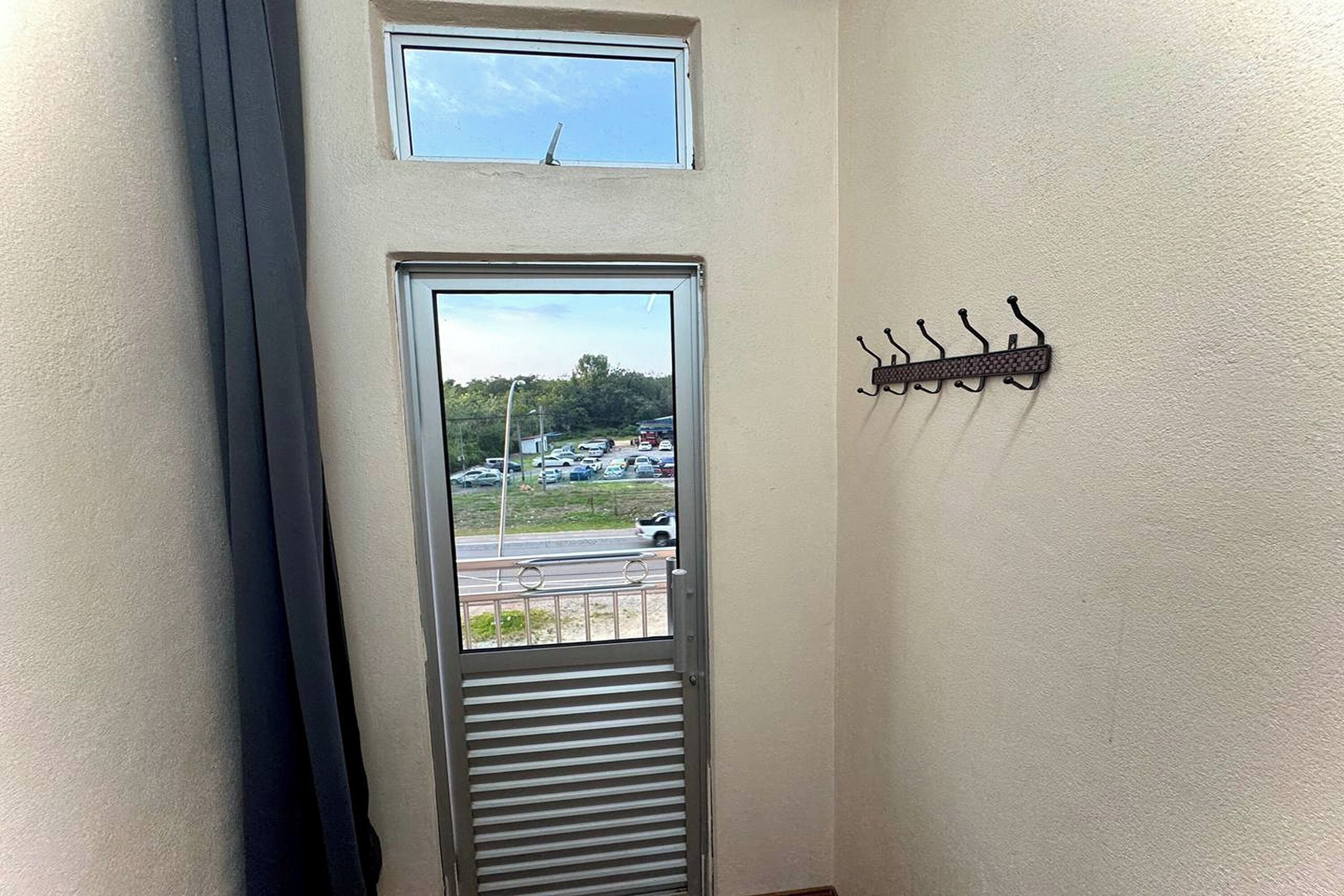 A door with a view of a parking lot and a small window above it.