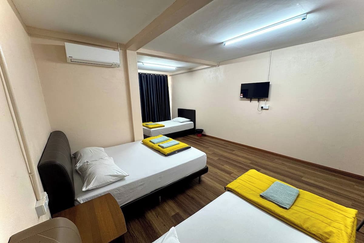 Habitación de hotel con dos camas, un escritorio, una silla, un aire acondicionado, un televisor de pantalla plana y piso de madera.