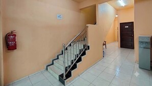 A staircase with metal railings, a fire extinguisher on the wall, and a water dispenser. - Hotel Rs Inn (Pasir Mas)