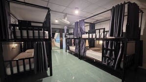 A dormitory room with bunk beds, a ceiling fan, and a visible bathroom. - Terminal Garage (Phuket)