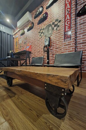 A rustic interior with a wooden table, chairs, a brick wall, and a sign indicating a garage. - Terminal Garage (Phuket)