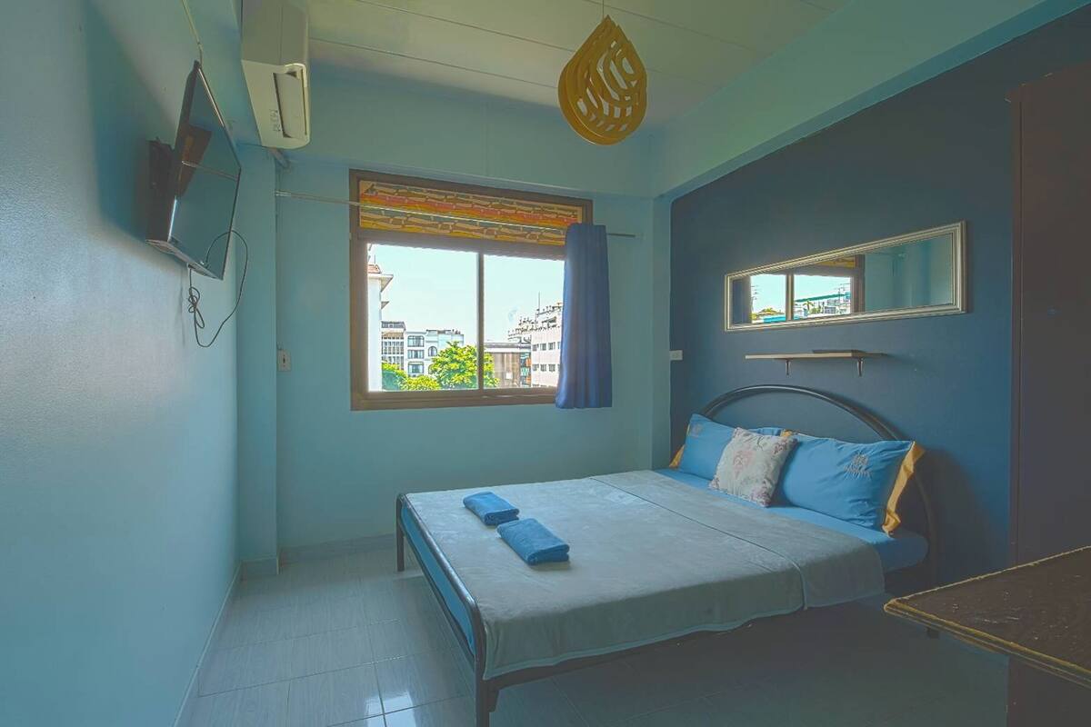 Una habitación con cama, ventana con vistas, espejo y aire acondicionado.