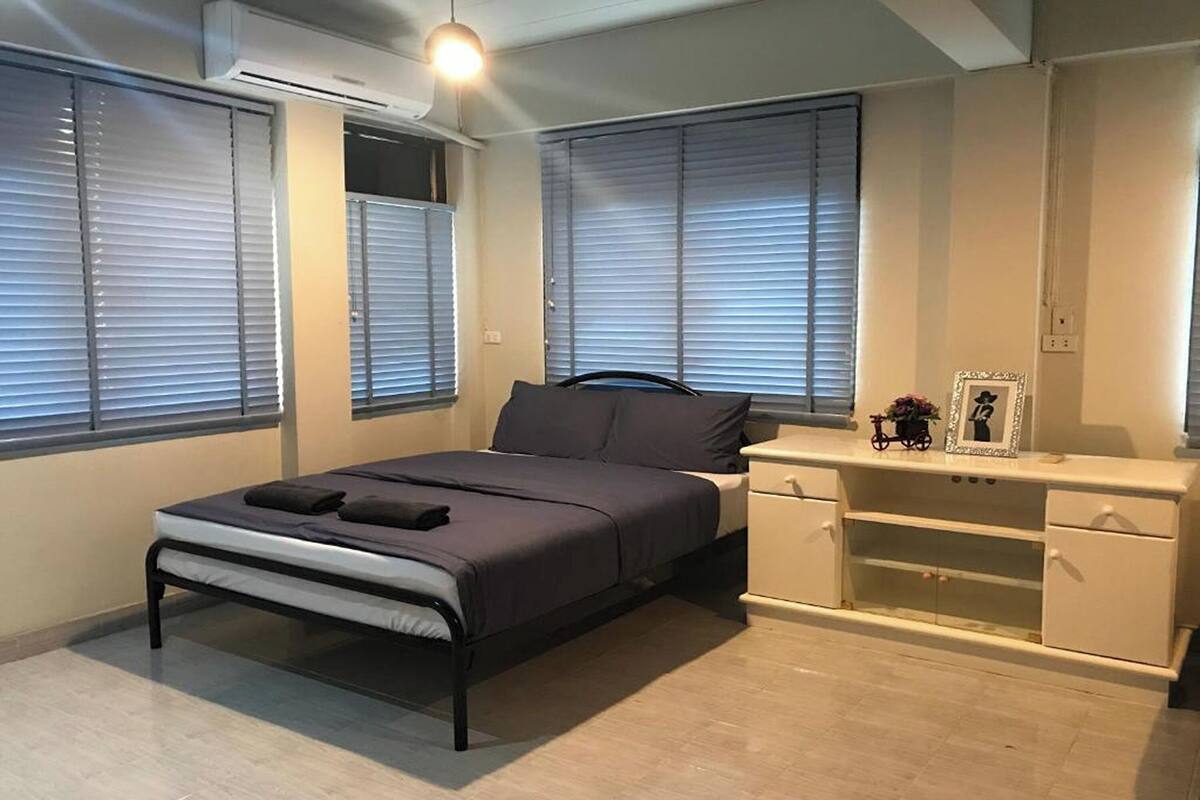 Un dormitorio con cama, mesitas de noche, escritorio y silla.