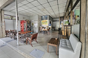 A spacious room with a large window, a sofa, a wooden table, and a dining area with chairs.