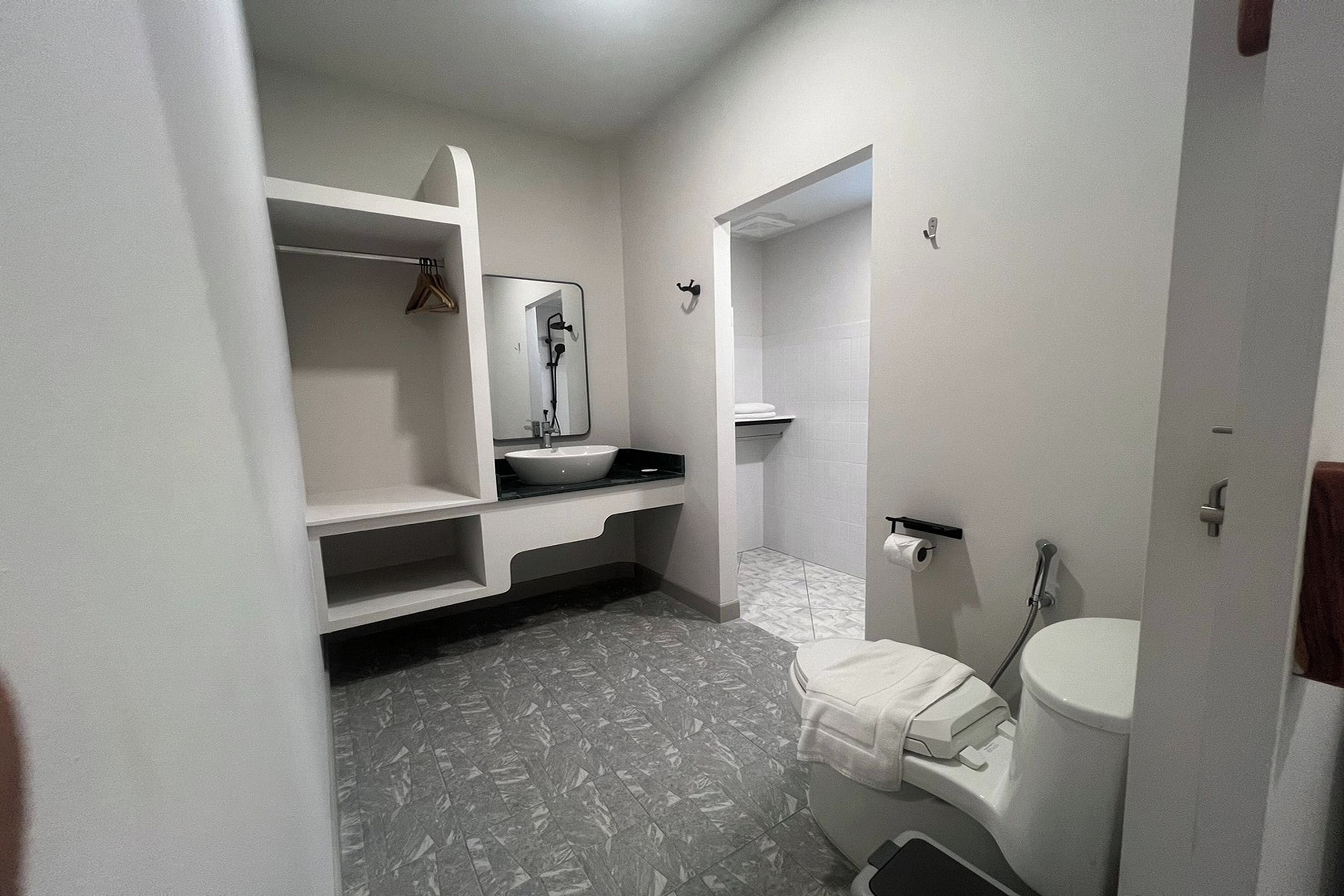 Un baño con un lavamanos blanco, un espejo, un perchero para toallas y un inodoro.