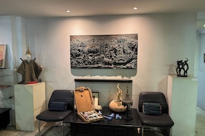 A room with a large black and white mural, two black chairs, a wooden chest, and a decorative Buddha statue. - Silp-Pa Phra Nakorn Si Ayutthaya (Ayutthaya)