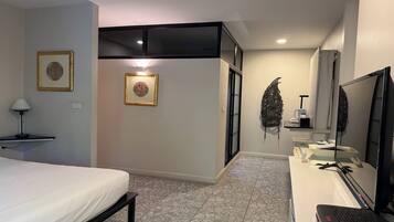 A hotel room with a bed, a desk with a computer, a TV, and framed pictures on the wall.