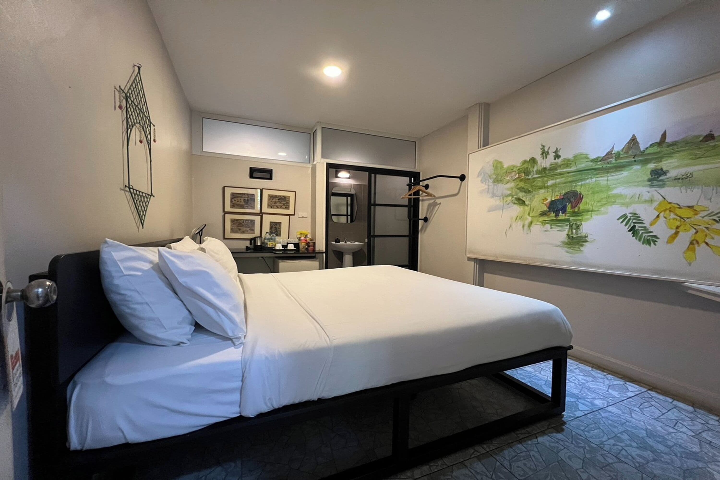 A bedroom with a bed, a desk, and a wall-mounted artwork.