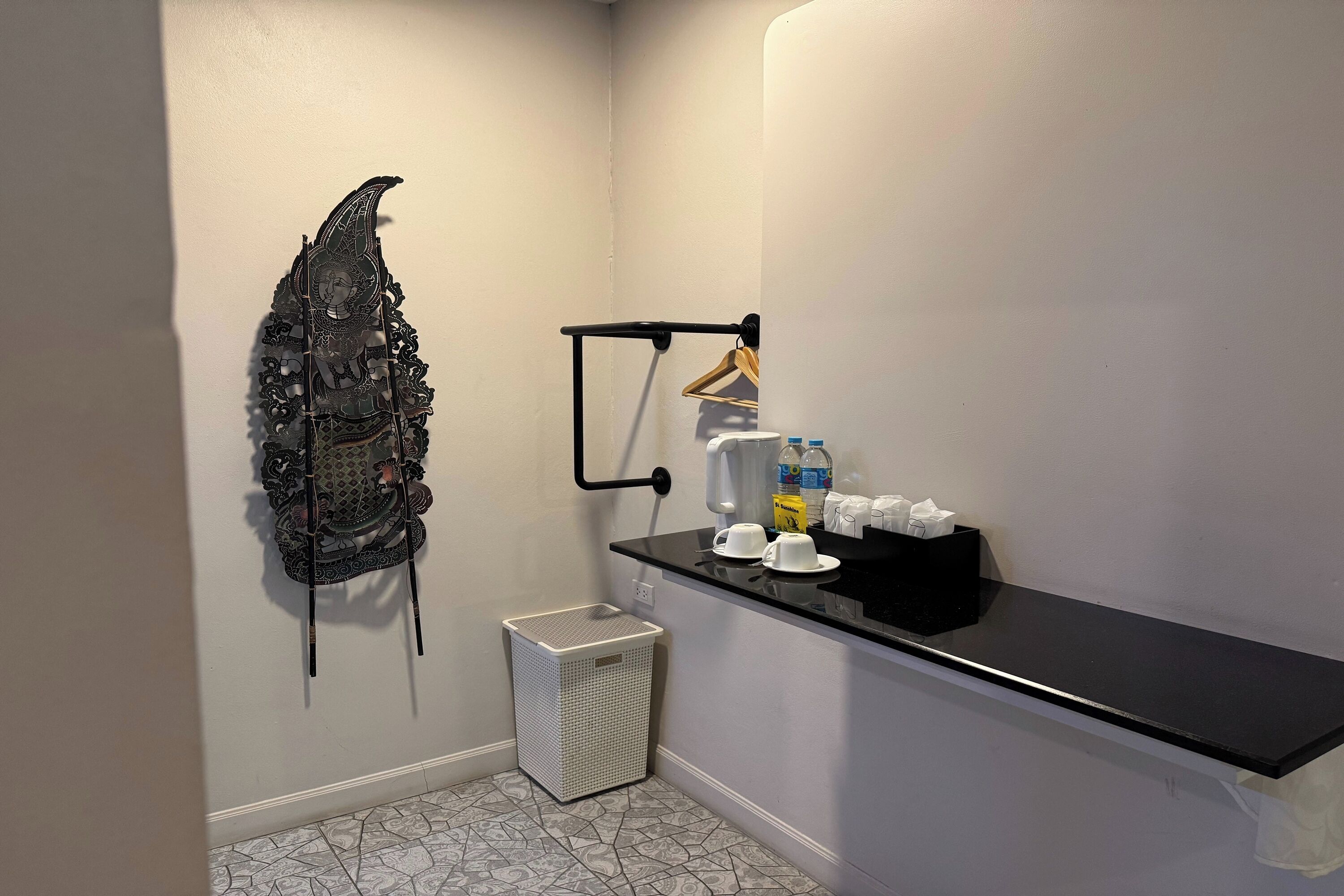 Un baño con toallero, un cubo de basura pequeño, repisas con artículos de tocador y piso estampado.