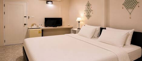 Una habitación de hotel con una cama, un escritorio con televisor, una lámpara y un equipo de aire acondicionado.