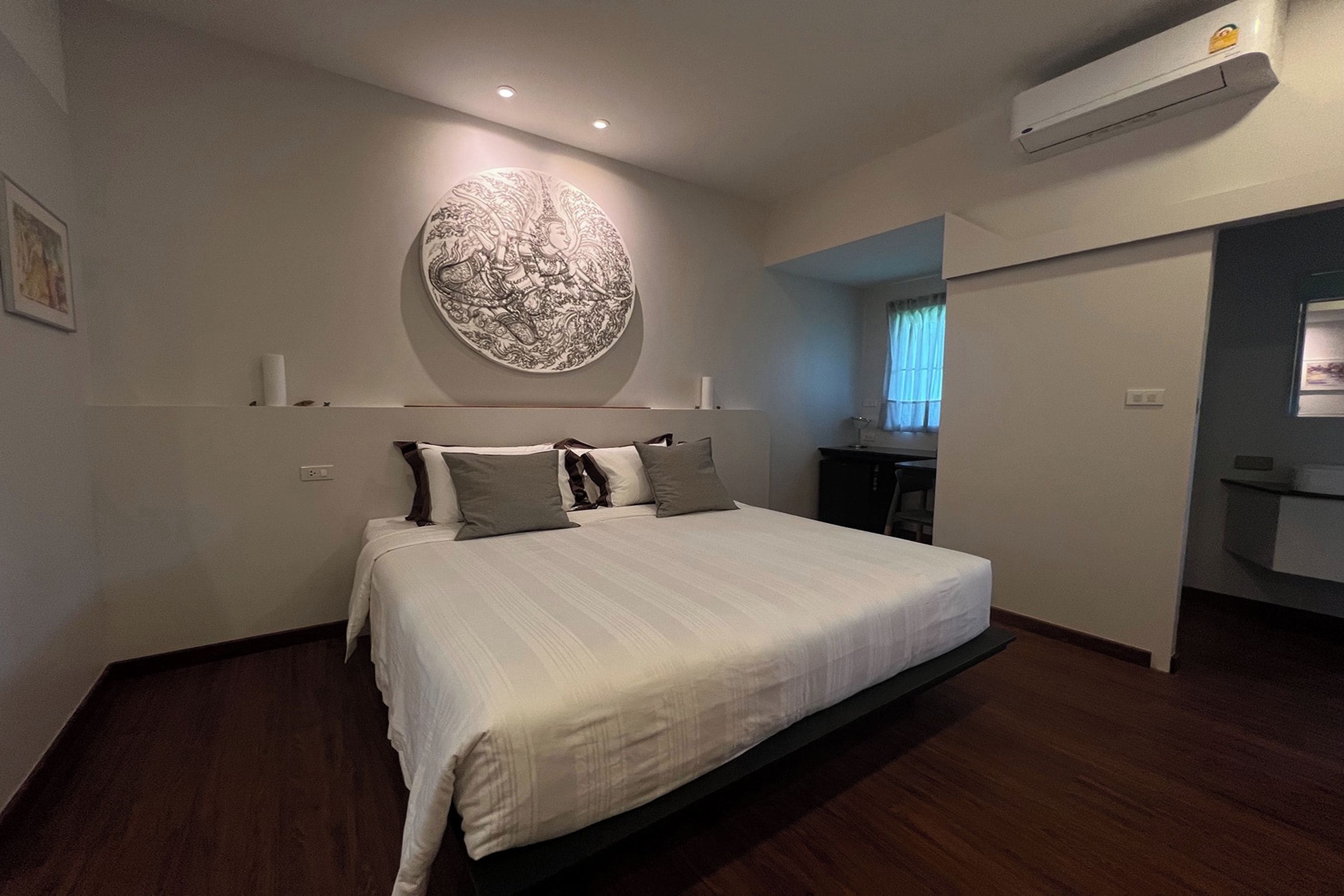 A modern bedroom with a large bed, a wall-mounted artwork, and a built-in air conditioning unit.