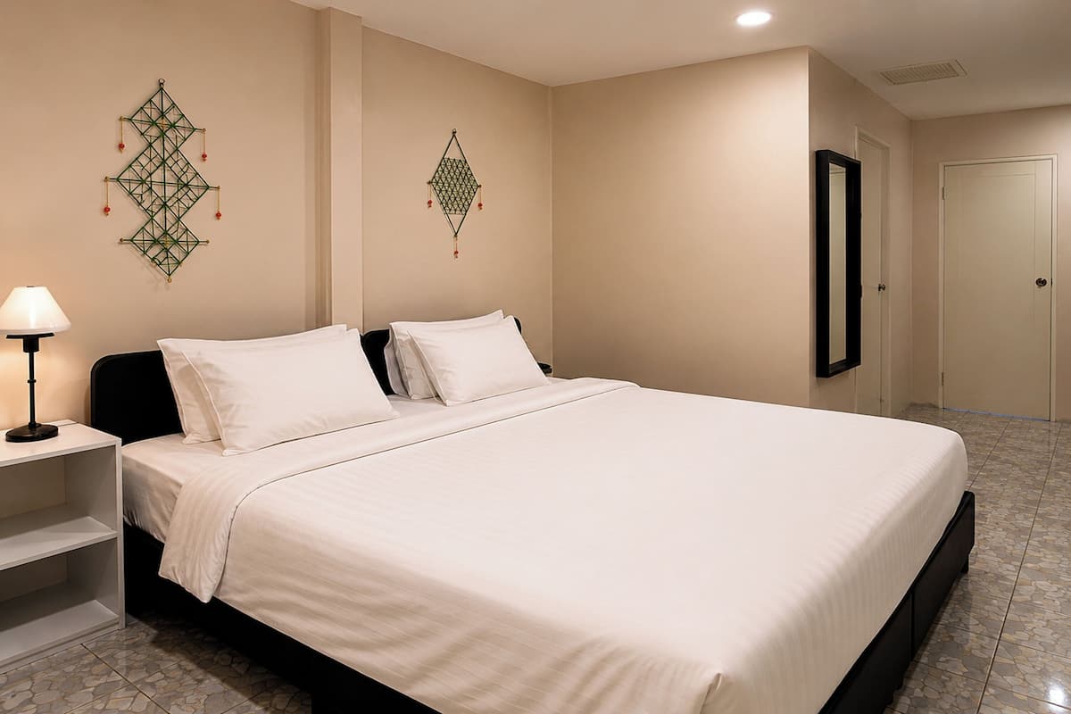 A neatly made bed with white linens, a bedside table with a lamp, and decorative wall hangings.