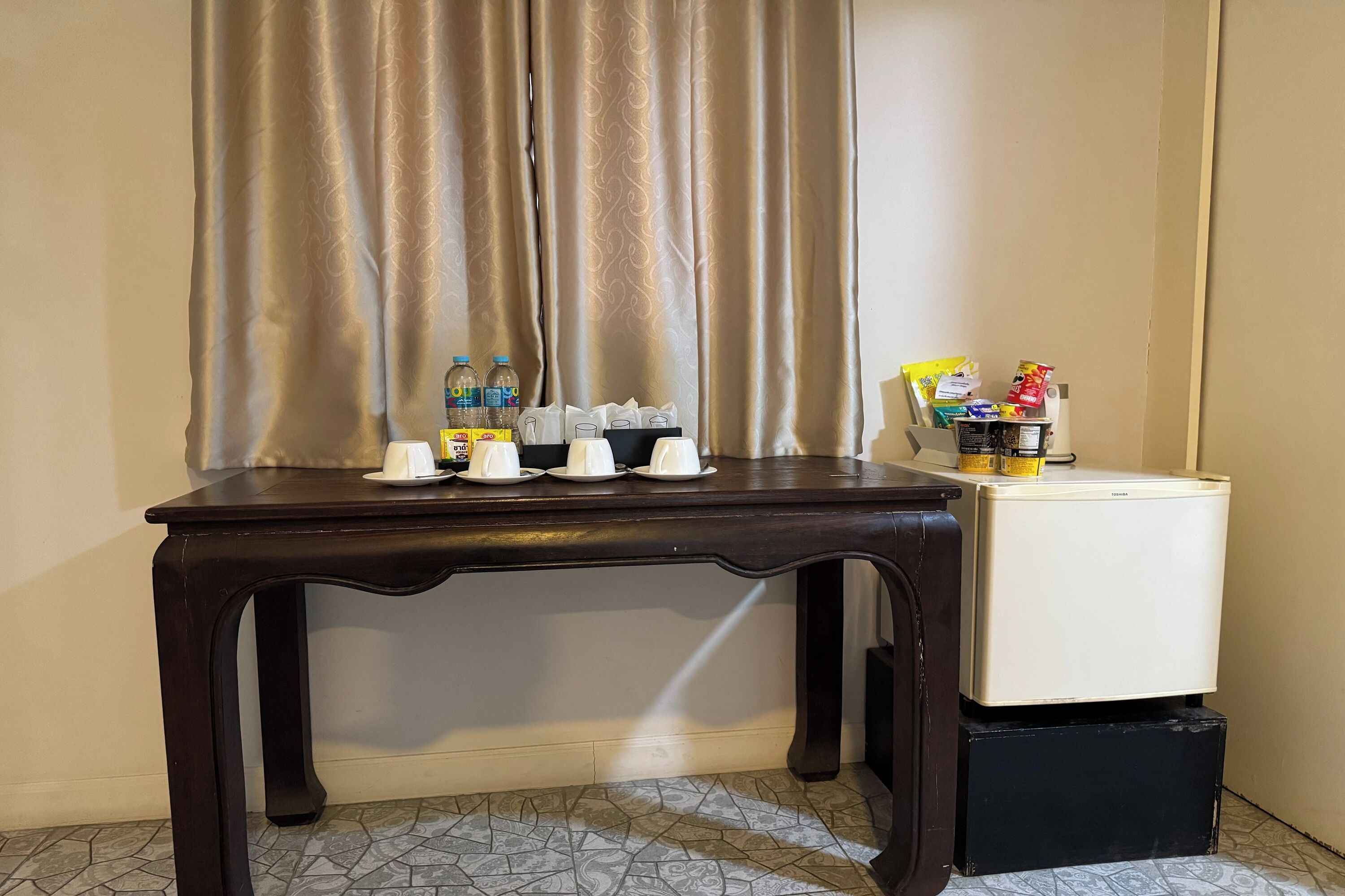 A small table with a refrigerator, a bottle of water, and some food items.