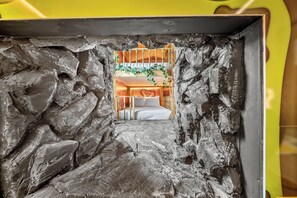 A room with a bunk bed, a heart-shaped wall decoration, and a window with a view.
