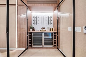A modern, compact room with a built-in wardrobe, a decorative wall with branches, and a small table with items.