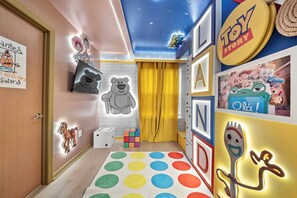 Una sala giochi per bambini con un soffitto a stelle, un pavimento colorato e numerosi giochi e decorazioni.