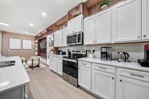 Una cucina moderna con mobili bianchi, elettrodomestici in acciaio inossidabile e un piano di lavoro in legno.