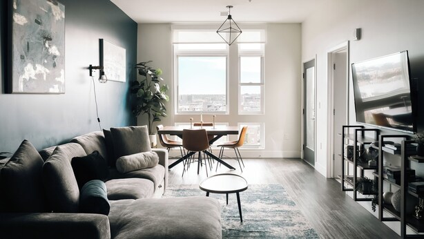 A modern living room with a sofa, dining table, chairs, a TV, and a large window with a city view. - Top-Floor 1BR Loft | Skyline Views | Walkable LoHi Denver (Denver)