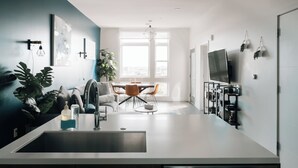A modern kitchen with a sink, dining table, chairs, and a TV. - Top-Floor 1BR Loft | Skyline Views | Walkable LoHi Denver (Denver)