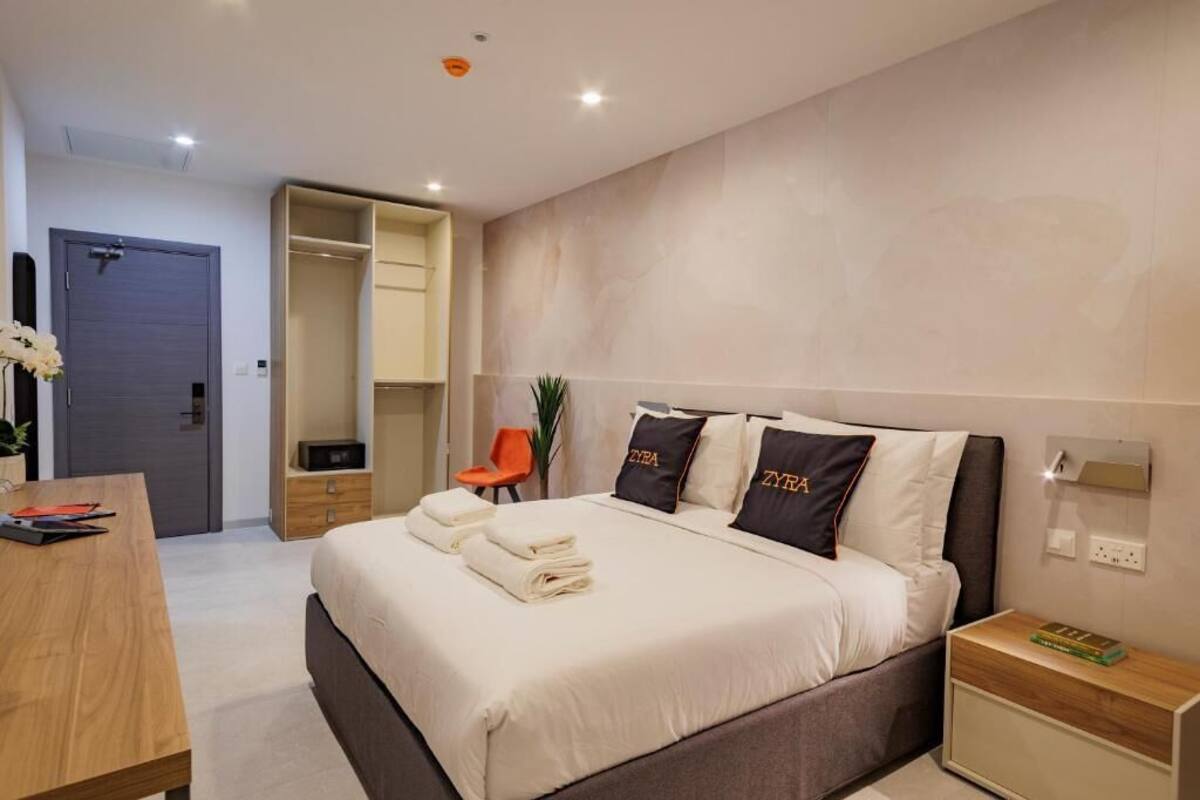 Una habitación de hotel moderna con cama, mesitas de noche, escritorio y armario.