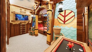 Une salle de jeux avec des meubles en bois, une fresque murale et une table de billard.