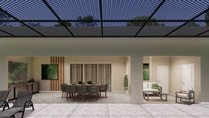 Un espace extérieur abrité comprenant une piscine, une table à manger avec des chaises et un coin salon avec un canapé et des fauteuils.