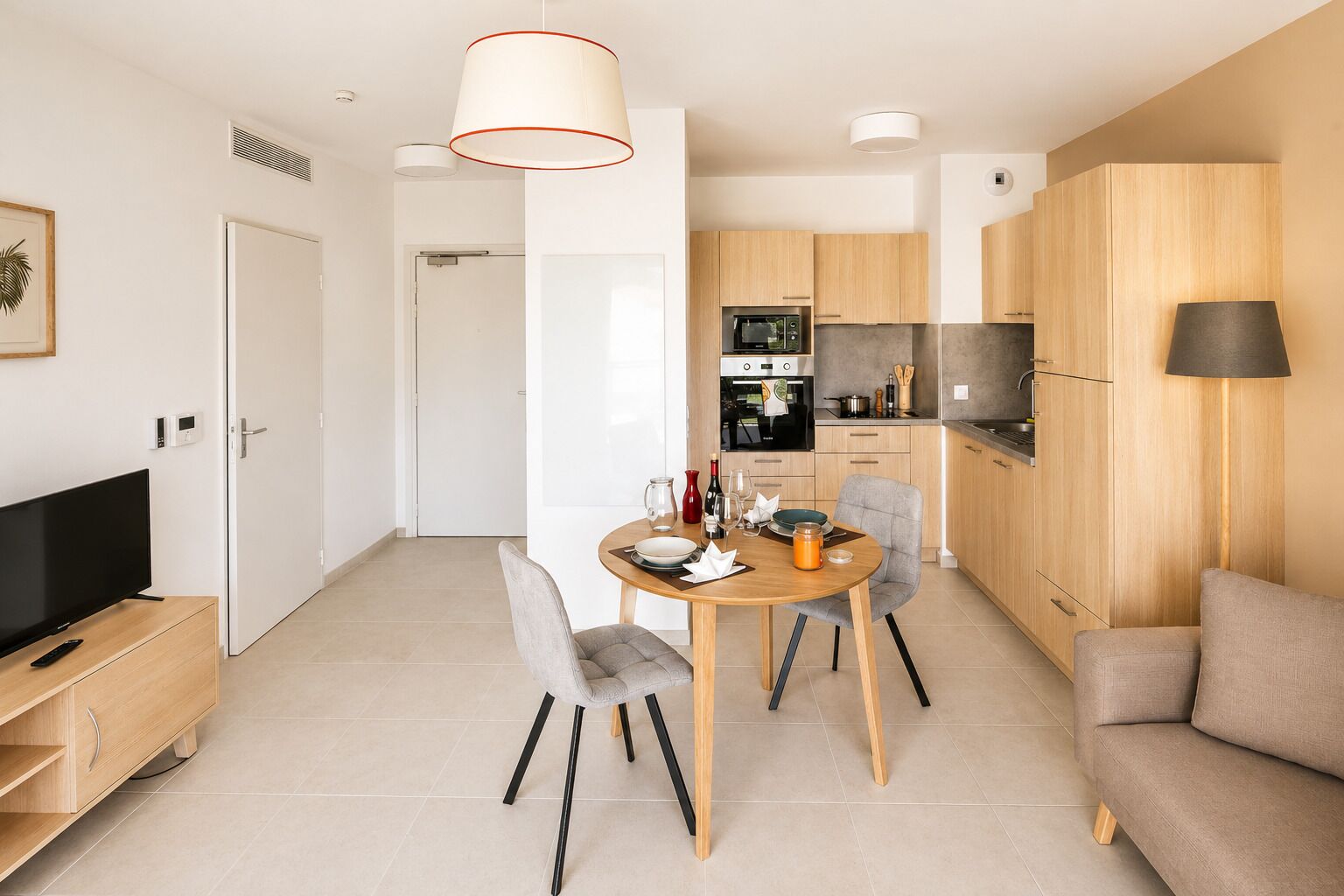 A modern kitchen with wooden cabinets, a dining table with chairs, a TV, and a sofa.