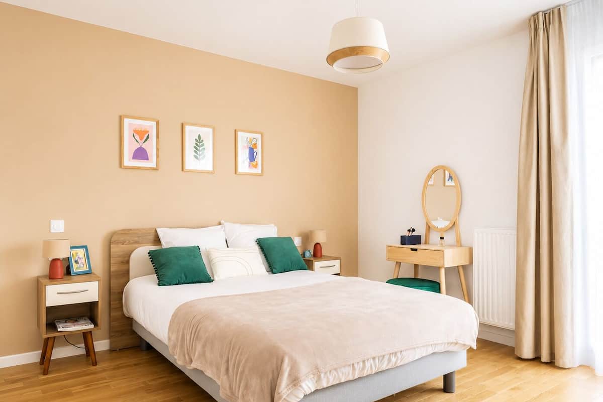 A bedroom with a bed, bedside tables, a dresser, a mirror, and framed artwork on the wall.