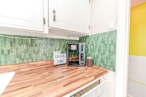 Una cocina con cafetera, un letrero que dice 'COFFEE TIME' y un salpicadero de azulejos verdes.