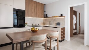A modern kitchen with a wooden table, two chairs, and a fruit bowl. - Villa Sea View, Saint George Horizon Villas (Rethymno)