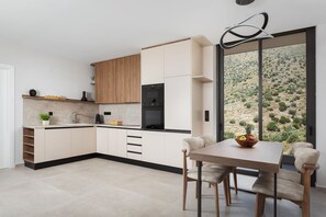 Een moderne keuken met een eethoek, grote ramen en uitzicht op een woestijnlandschap.