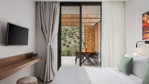 Una habitació d'hotel moderna amb un llit, una televisió, una prestatgeria de fusta, una taula de menjador i vista a l'exterior.