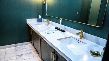 A bathroom with two sinks, a mirror, and a towel dispenser.