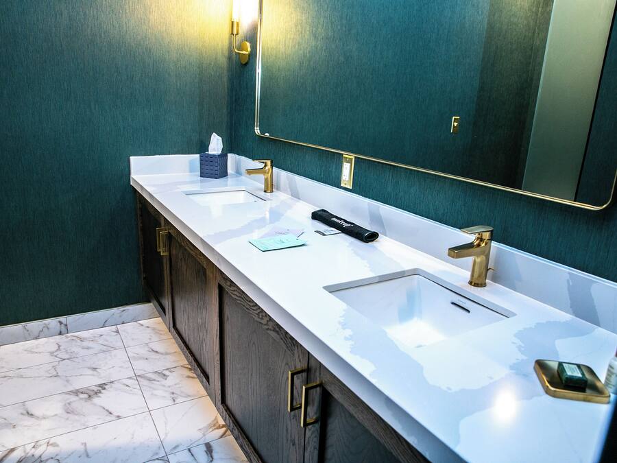A bathroom with two sinks, a mirror, and a towel dispenser.