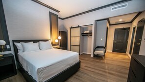 A modern hotel room with a large bed, bedside lamps, a wardrobe, and a chair.
