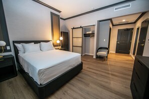 Ett modernt hotellrum med en stor säng, sänglampor, en garderob och en stol.