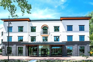 A modern hotel with a prominent arched entrance, large windows, and a sign reading 'The Cardinal Hotel.'