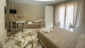A hotel room with a bed, a desk, a wardrobe, and a television. - CASA SÒL (Tropea)