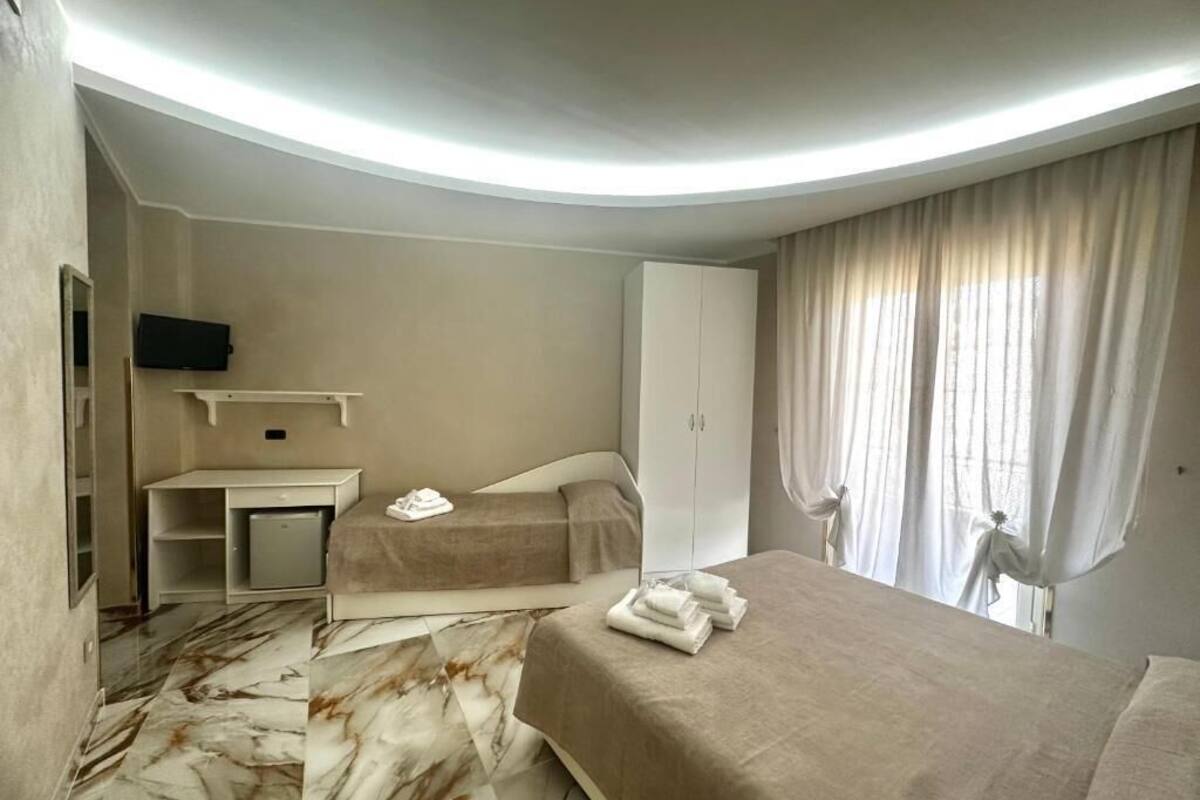 Una habitación de hotel con cama, escritorio, armario y televisor.