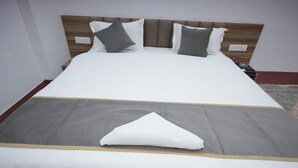 Ein Bett mit einer grauen Tagesdecke, weißen Kissen und einem hölzernen Kopfteil.
