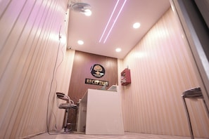 A reception area with a wooden panel wall, a reception desk, and a chair. - Hotel Subarnrekha Heritage (Ranchi)