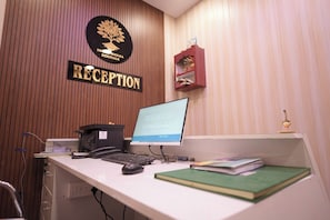 A reception desk with a computer, a telephone, and a shelf with books. - Hotel Subarnrekha Heritage (Ranchi)