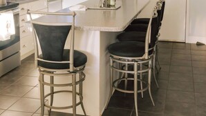 Una cocina con barra, armarios blancos, un lavamanos y una puerta con picaporte.