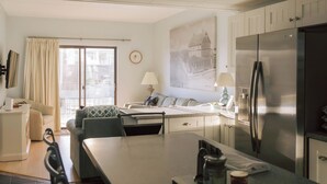 Una cocina moderna con un refrigerador grande, una mesa de comedor y un sofá en la zona de estar contigua.