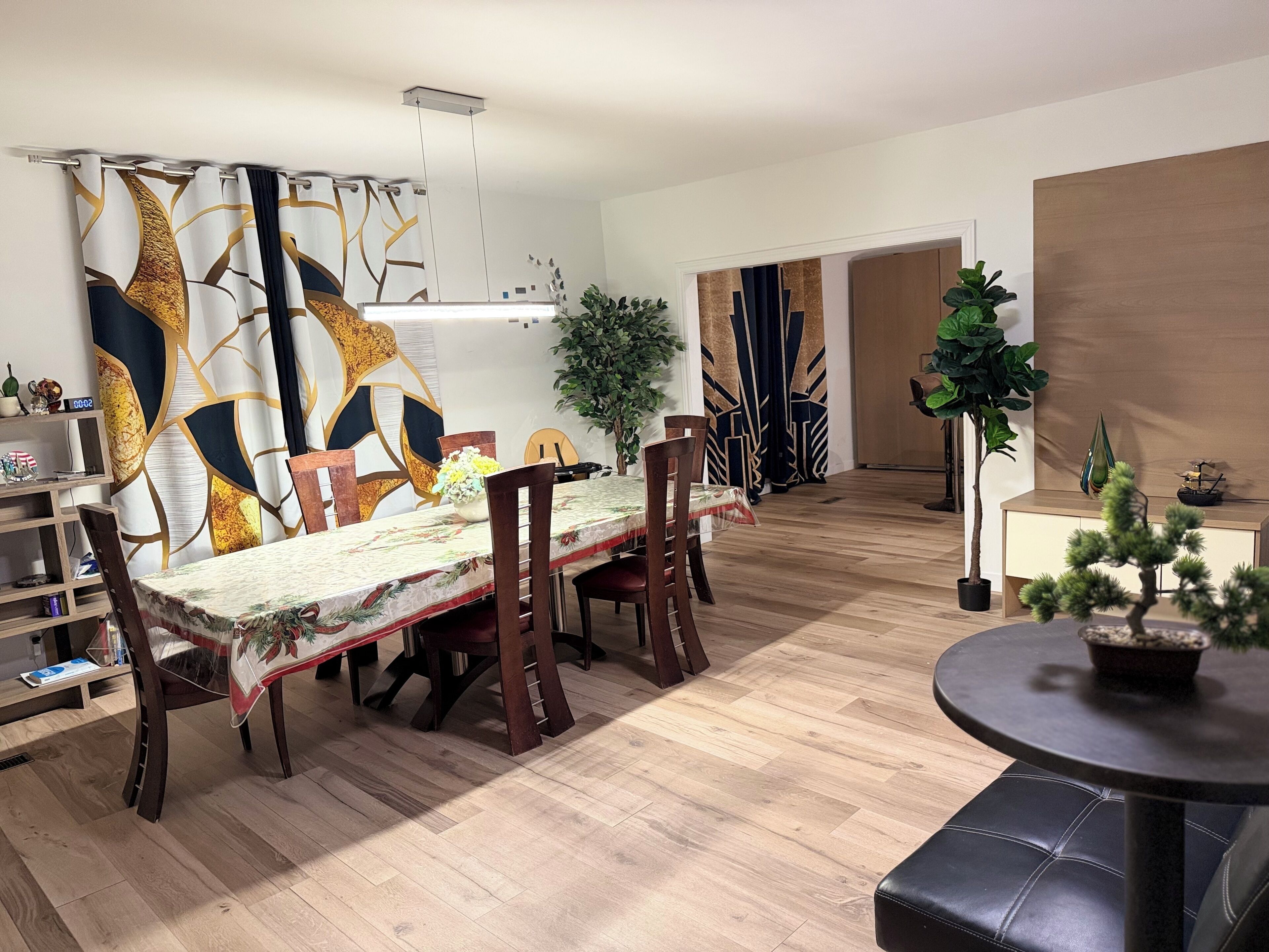 A dining area with a table, chairs, a potted plant, and a small round table with a plant.