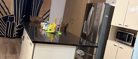 Una cocina moderna con una isla central, electrodomésticos de acero inoxidable y un microondas.