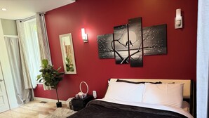A bedroom with a bed, a nightstand, a wall-mounted light, a painting, and a potted plant. - Huge, immaculate Chris manor house 5 minutes from amusement park and gym (Saint-Augustin-de-Desmaures)